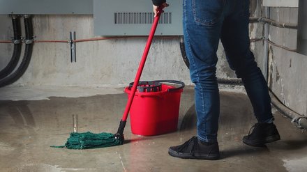 Symbolbild Leitungswasserschaden zeigt nassen Boden, welcher mit Mop gewischt wird. 