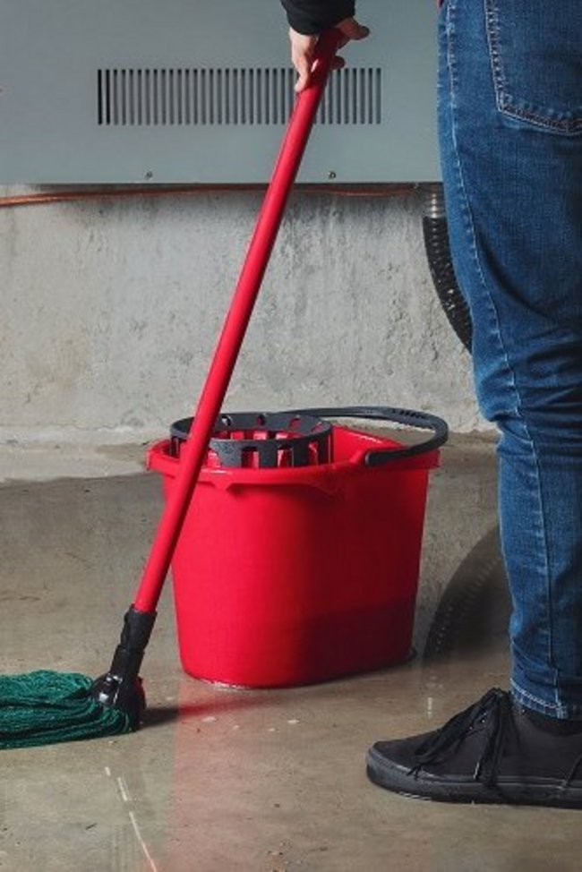 Symbolbild Leitungswasserschaden zeigt nassen Boden, welcher mit Mop gewischt wird. 