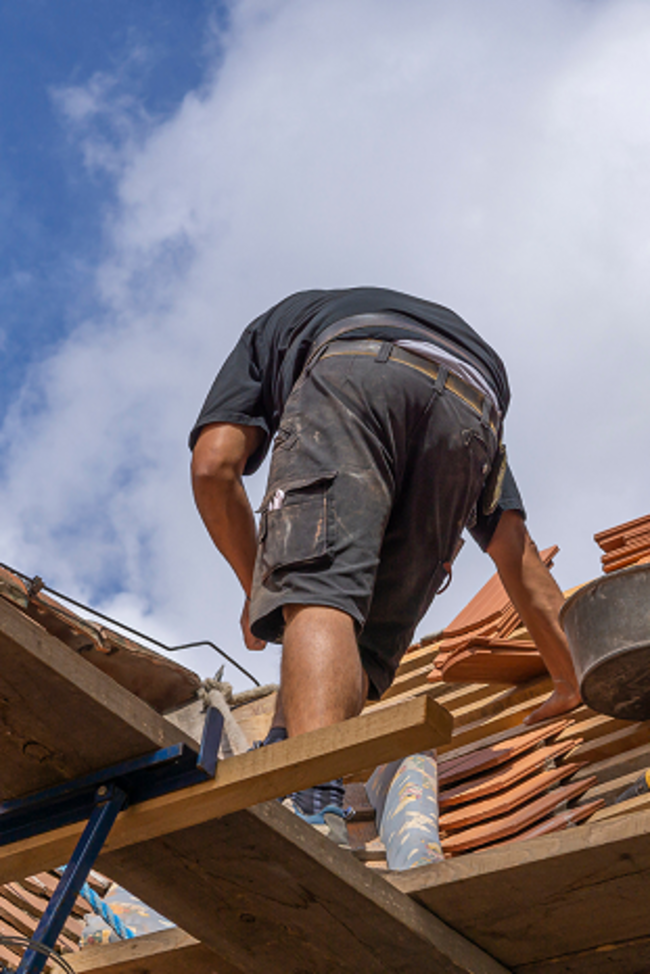 Symbolbild Unterversicherung. Dachdecker arbeitet auf Dach.