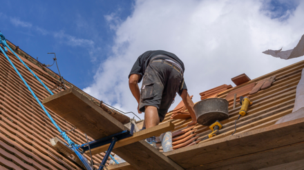 Symbolbild Unterversicherung. Dachdecker arbeitet auf Dach.