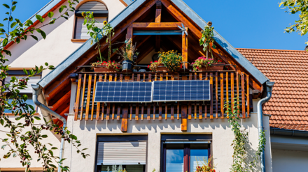 Bild zeigt Einfamilienhaus mit Giebeldach und PV-Anlage auf der Balkonbrüstung