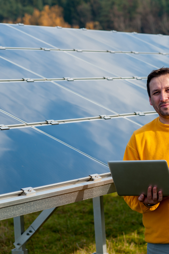 Ertragsausfall Photovoltaik. Bild zeigt Mann mit Laptop vor einer PV-Anlage