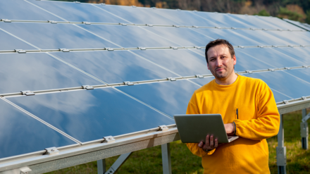 Ertragsausfall Photovoltaik. Bild zeigt Mann mit Laptop vor einer PV-Anlage