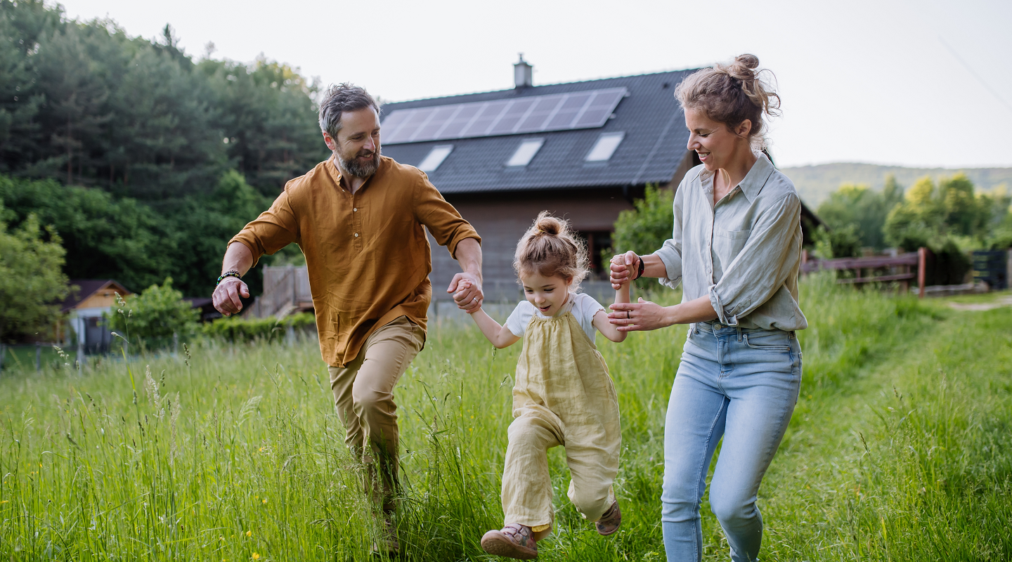 Familie läuft vor Ferienhaus durch das hohe Gras 